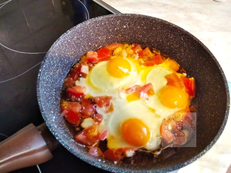 Разбить яйца на сковородку с помидорами
