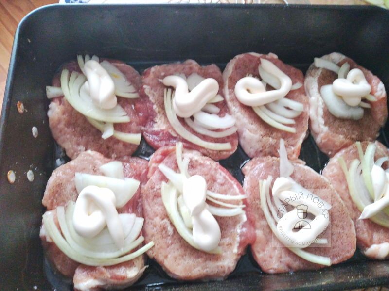 Выкладываем на мясо лук, майонез и тертый сыр